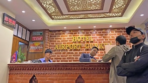 A hotel reception desk with a brick wall background and a ceiling with intricate patterns. - Hotel Airport Holiday (Kathmandu)