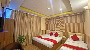 A hotel room with two beds, a wooden floor, a checkered wall, and a ceiling with recessed lighting. - Hotel Airport Holiday (Kathmandu)