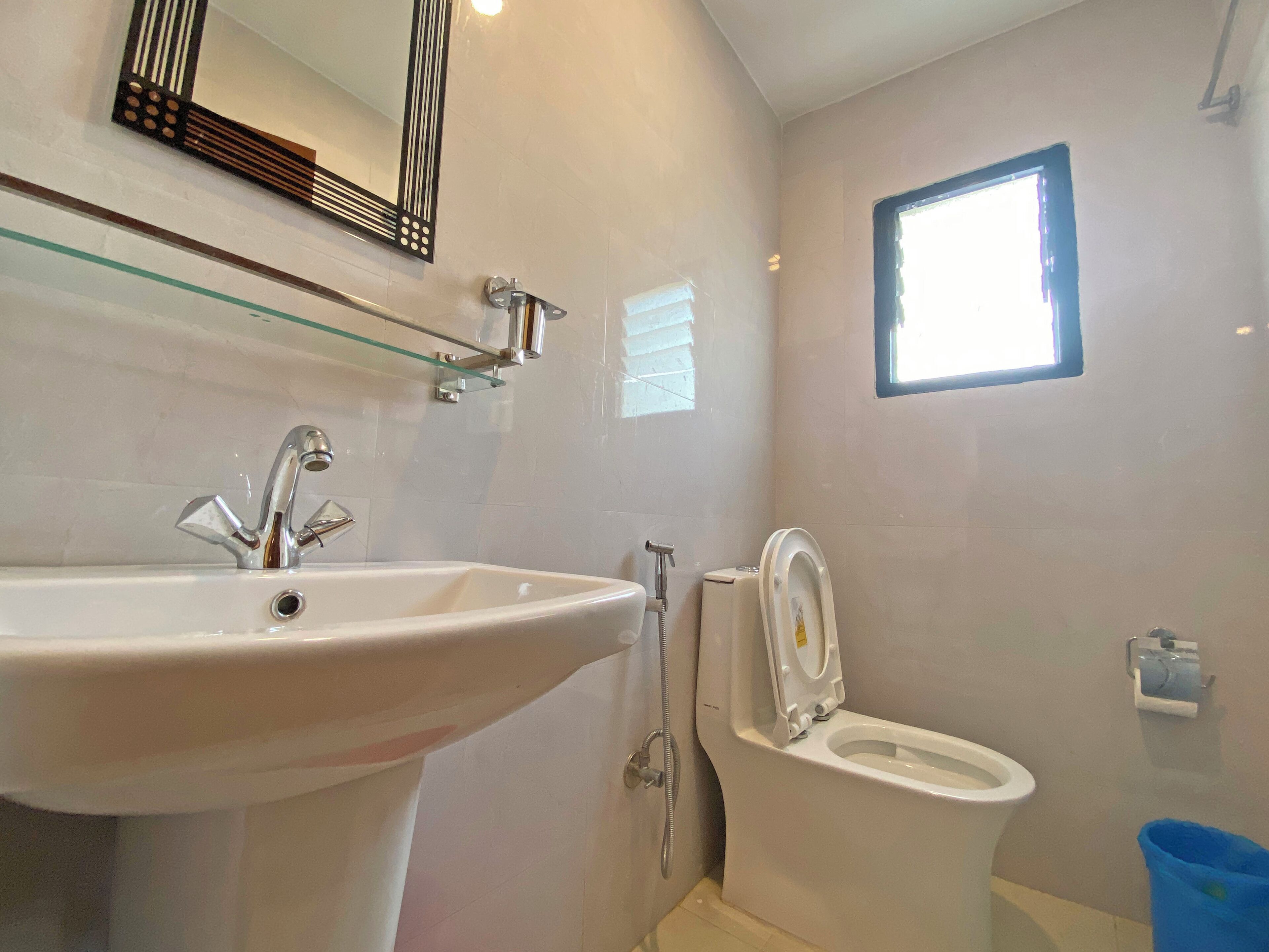 A bathroom with a sink, toilet, and a small window.