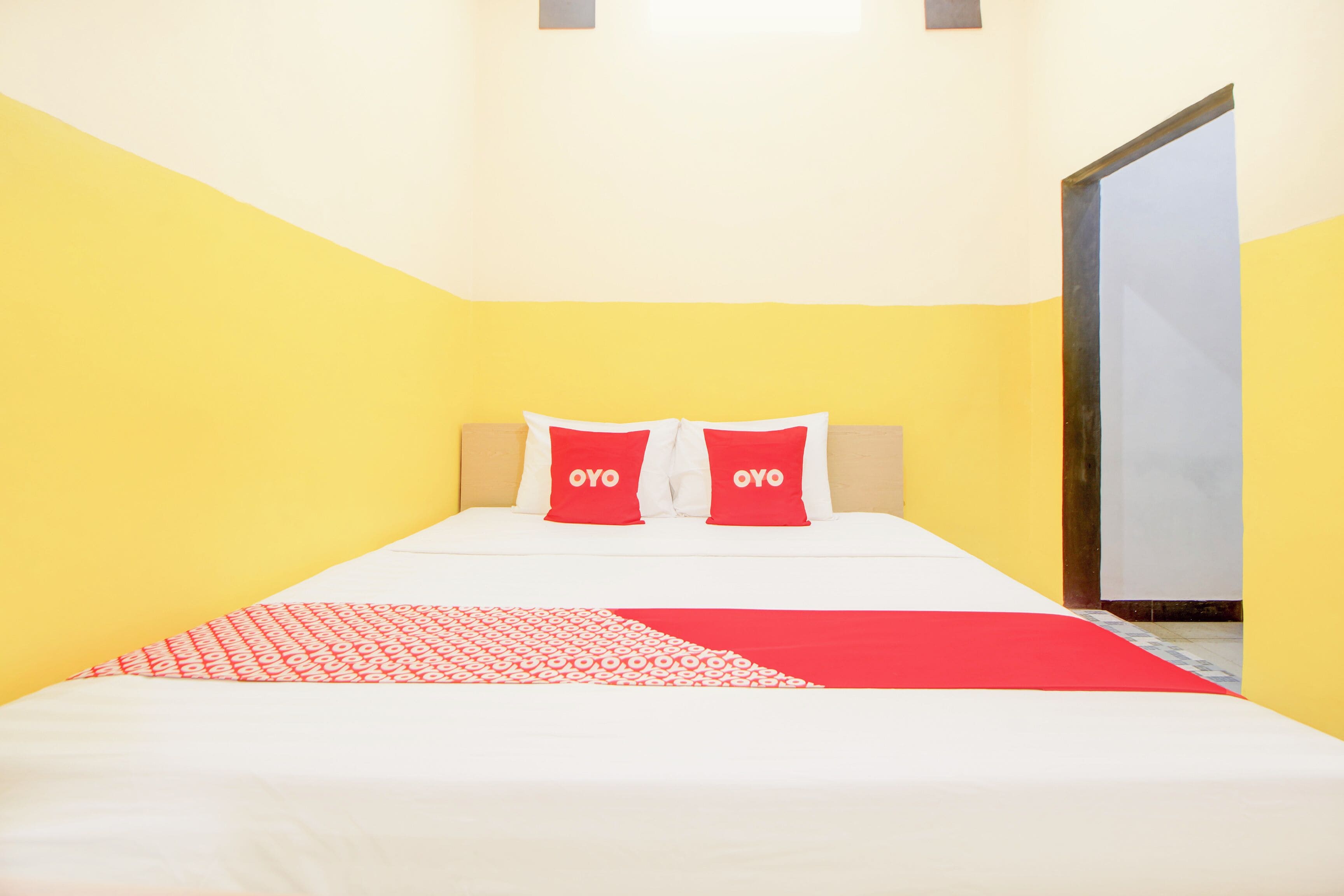 A bed with two pillows, a red and white patterned blanket, and a red throw.