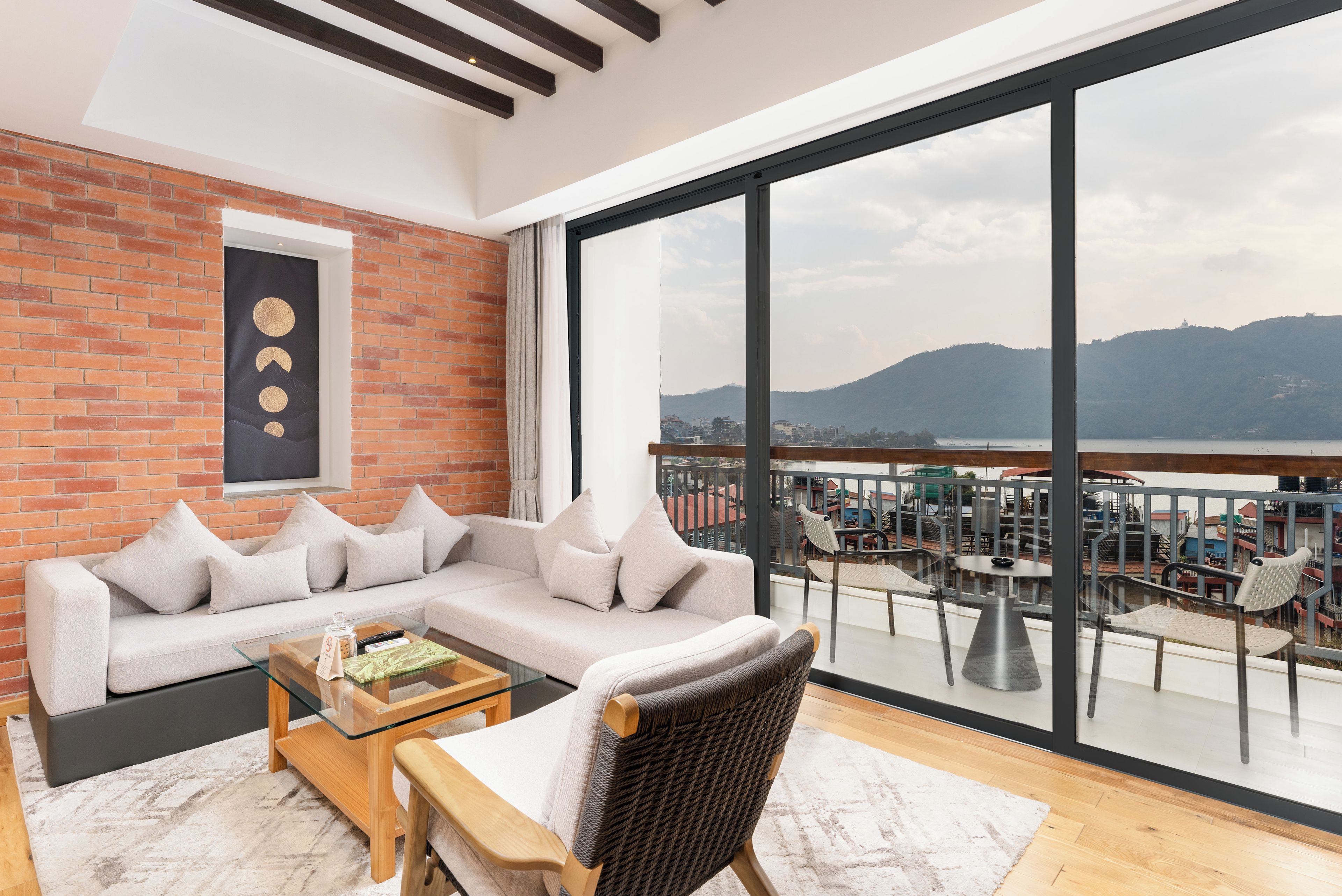 A modern living room with a sofa, a glass coffee table, and a view of a balcony with outdoor seating.