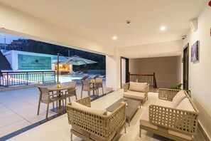 A spacious balcony with outdoor furniture, a pool, and a view of the surrounding area. - Atithi Suites  (Pokhara)