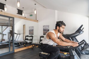 A gym with treadmills, weight machines, and a mirror wall. - Atithi Suites  (Pokhara)