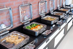 A buffet with various food items in clear containers, arranged on a black countertop with a brick wall in the background. - Atithi Suites  (Pokhara)