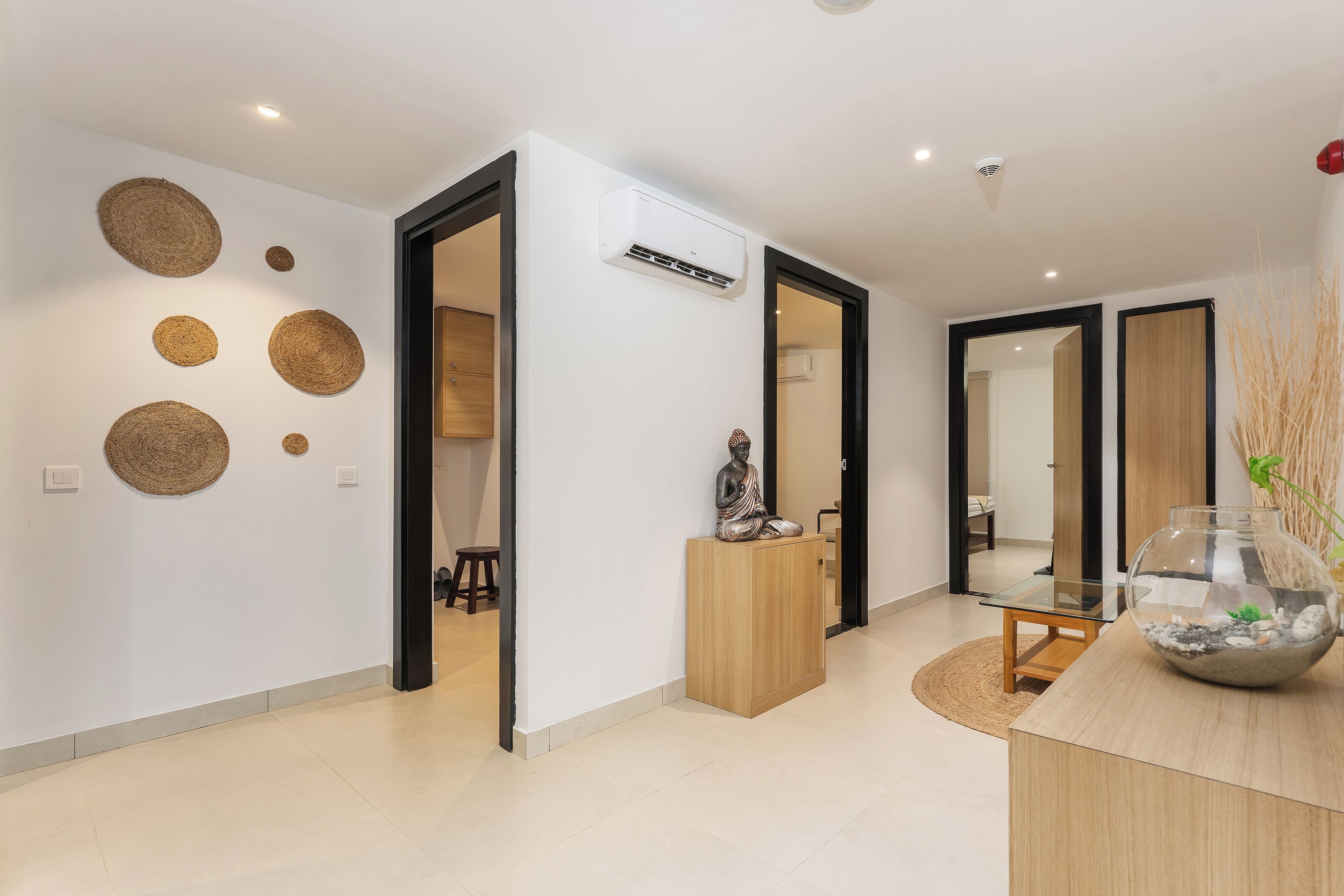 A modern interior with a wooden cabinet, a glass table, and a decorative fish bowl.