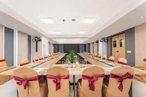 A conference room with a long table, chairs with red sashes, a potted plant, and a door on the right. - Atithi Suites  (Pokhara)