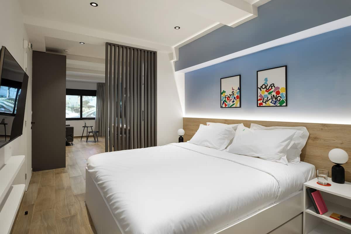 Ein modernes Schlafzimmer mit einem großen Bett, einem Fernseher und Kunstwerken an der Wand.