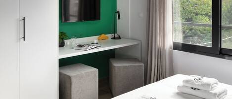 A modern bedroom with a bed, a desk, and a TV.