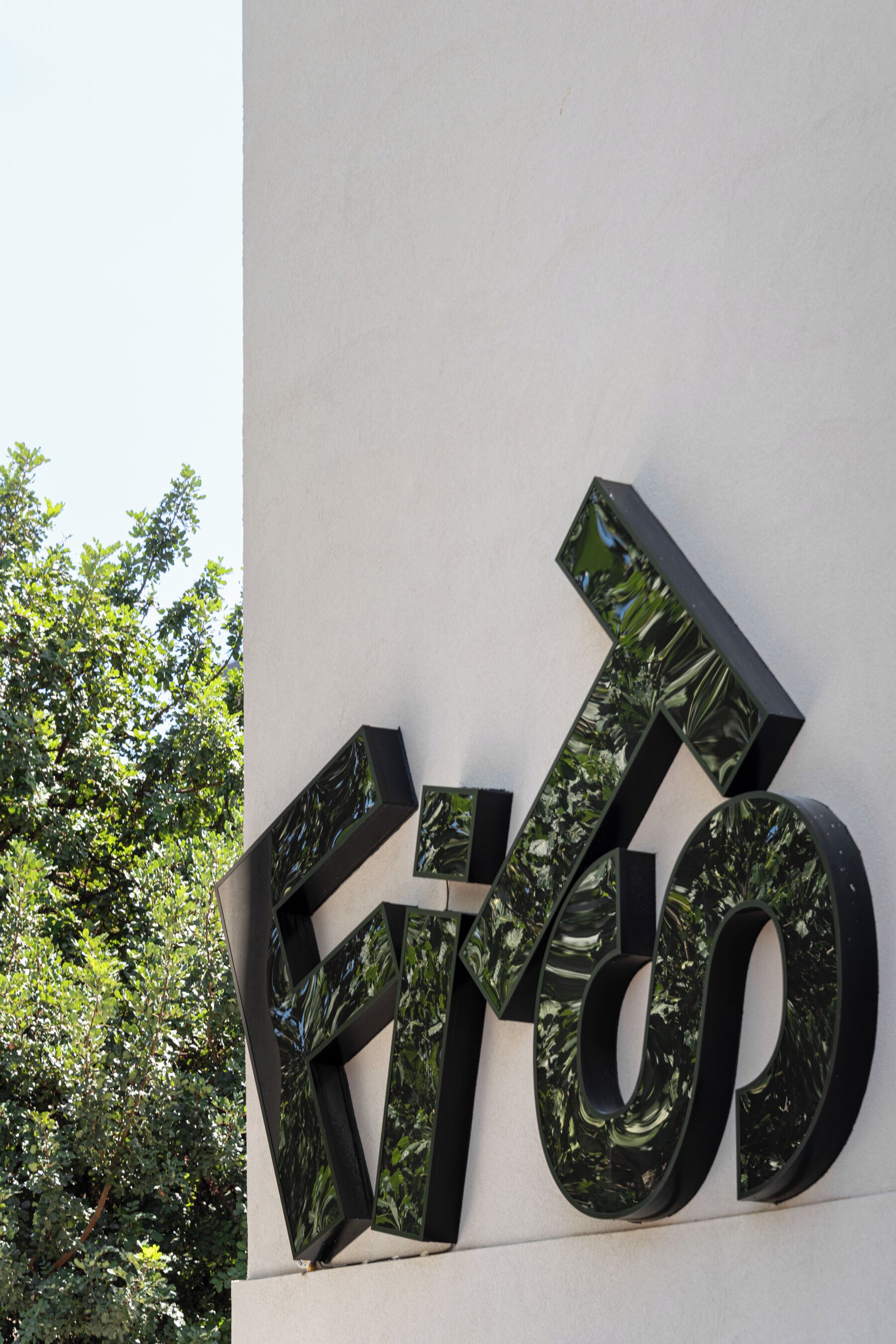 A large, reflective sign with the letters "KIR" on a white wall.