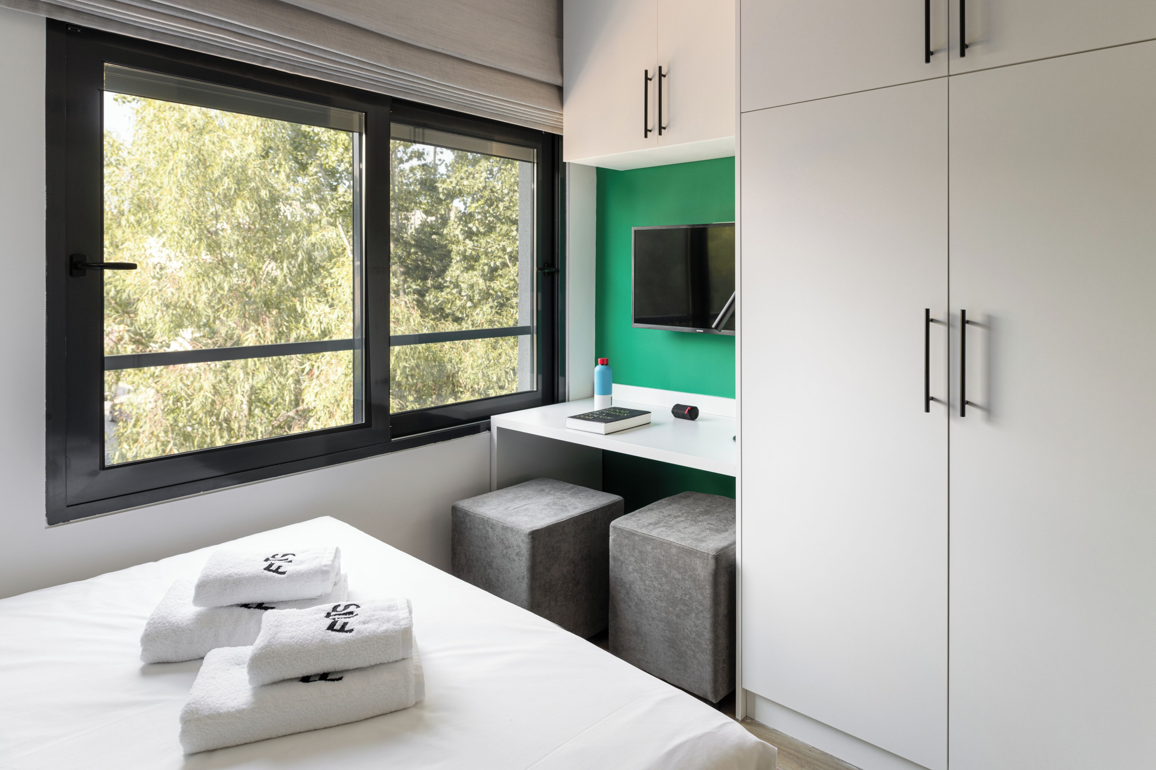 A modern hotel room with a bed, a desk, and a TV.