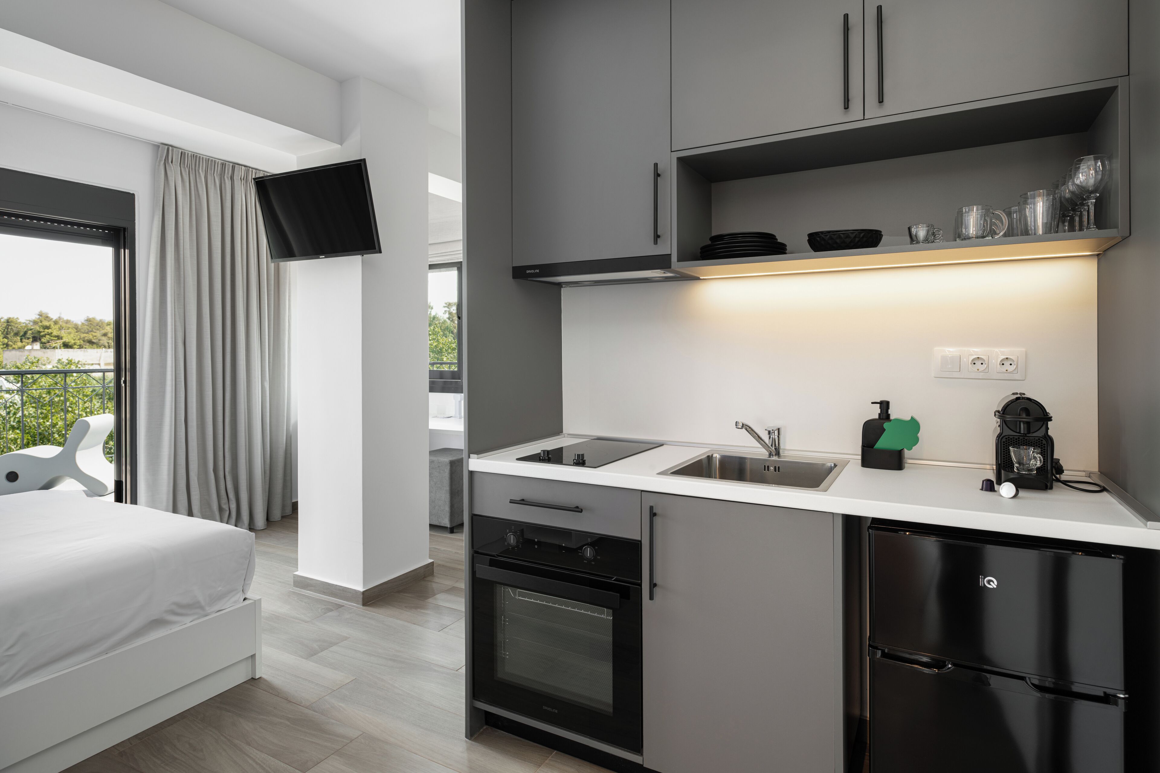 Una kitchenette moderna con horno integrado, un lavamanos y una cafetera.