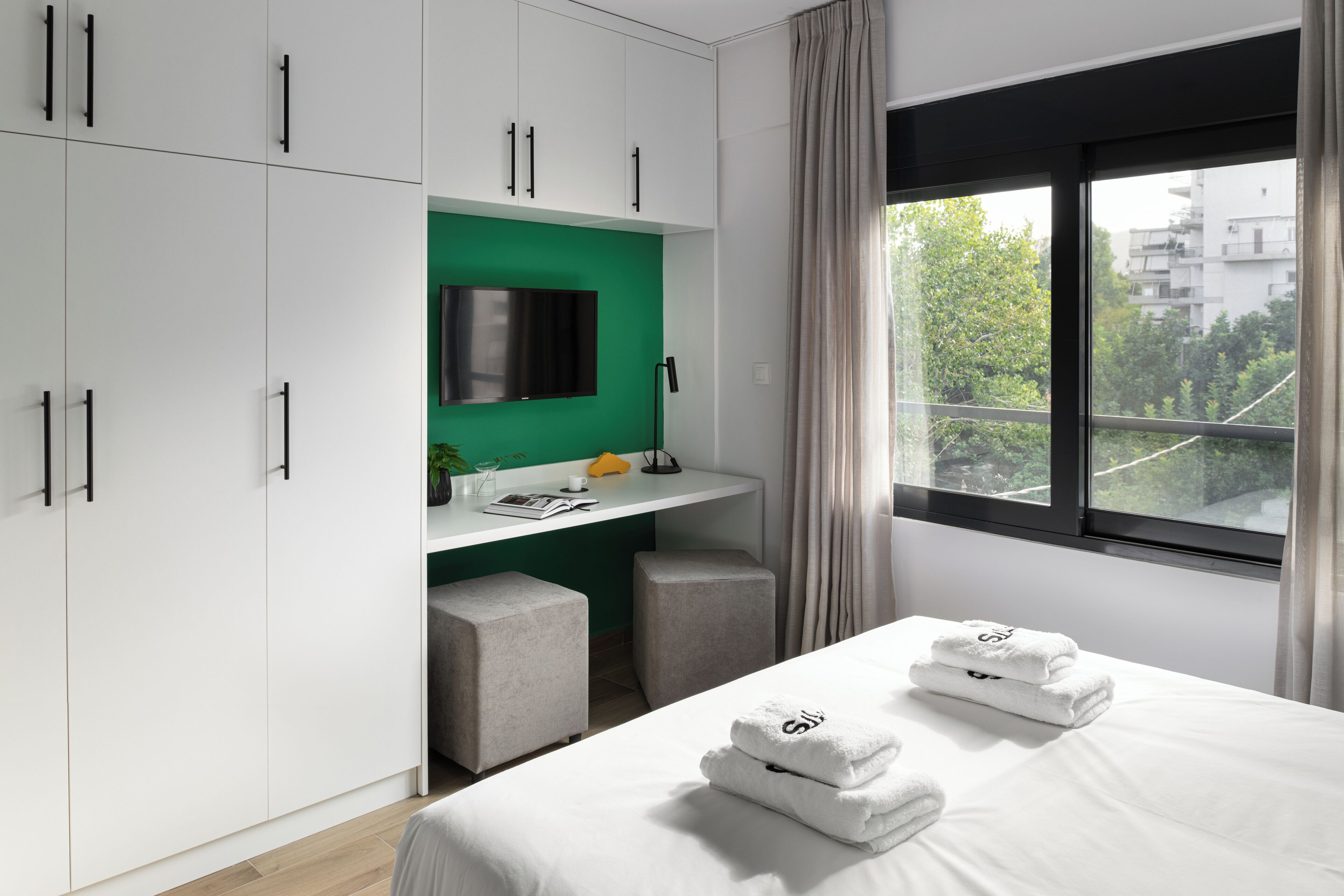 A modern hotel room with a bed, a desk, and a TV.