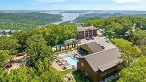A hotel with a swimming pool, outdoor seating, and a view of a river. - House of FUN! Games, Lakeview, Bunkroom! (Branson)