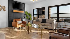 A modern living room with a flat-screen TV, a glass coffee table, leather sofas, and large windows with a view. - House of FUN! Games, Lakeview, Bunkroom! (Branson)
