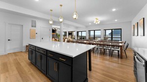 A spacious kitchen with a large island, black cabinets, and gold pendant lights. - House of FUN! Games, Lakeview, Bunkroom! (Branson)