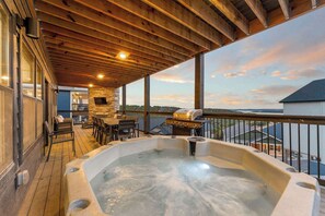 Une terrasse en bois avec un jacuzzi, des sièges d’extérieur et un barbecue.