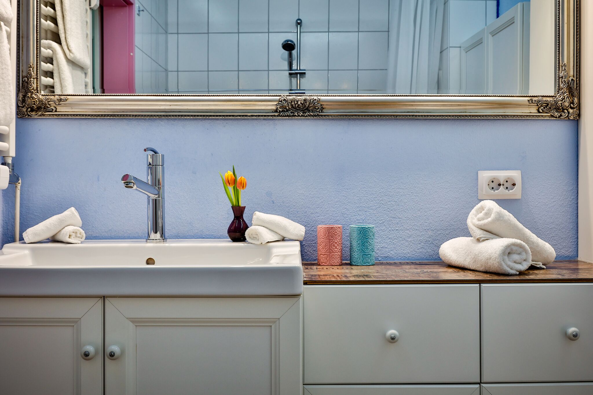 A bathroom with a sink, mirror, and towel rack.