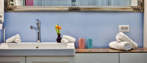 A bathroom with a sink, mirror, and towel rack.