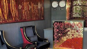 A reception area with a red carpet, black leather chairs, a reception desk with geometric patterns, and clocks on the wall. - Sam hotel Tbilisi (Tbilisi)
