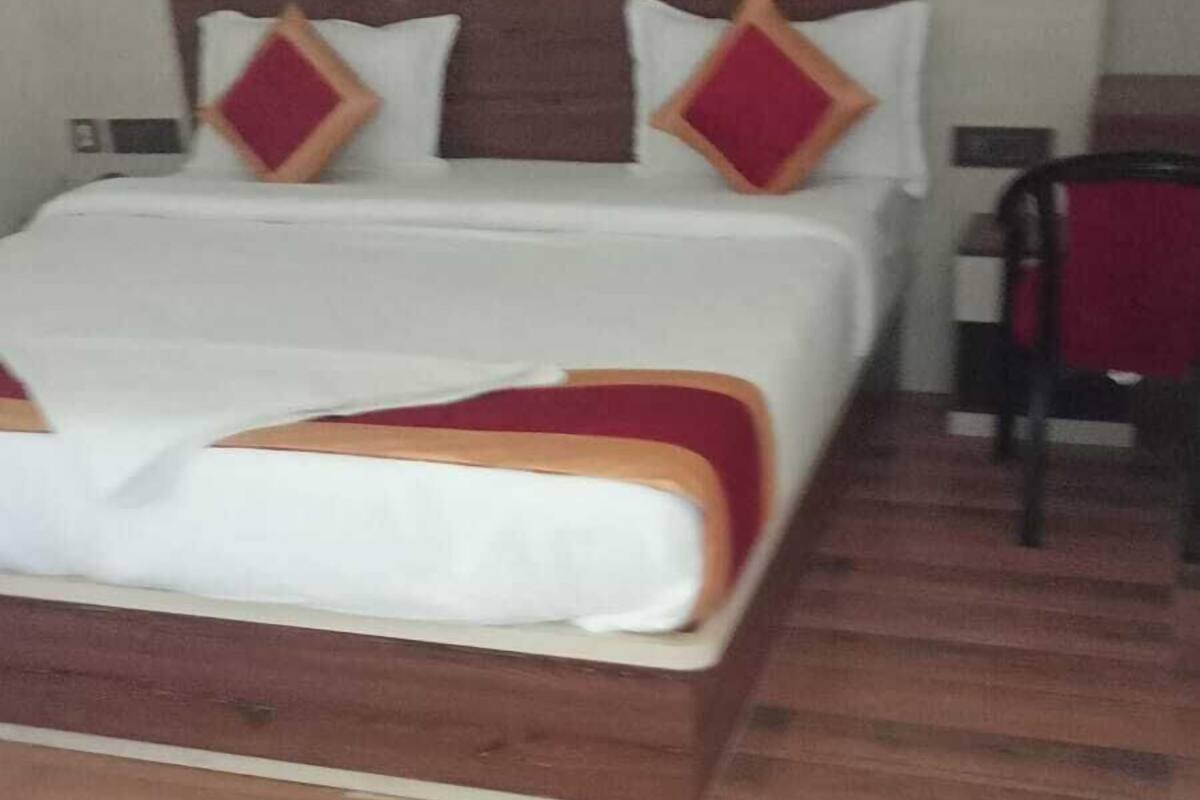 Une chambre d’hôtel avec un grand lit, une tête de lit en bois et une décoration aux couleurs rouge et blanche.