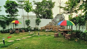 Um jardim com uma ponte de madeira, degraus de pedra e guarda-sóis coloridos.