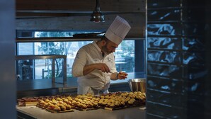 A chef preparing food in a kitchen with large windows and a view of trees outside. - Blu70 (Staletti)