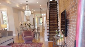 A spacious living area with hardwood floors, a staircase, a dining area, and a modern kitchen.