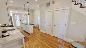 A modern kitchen with a central island, wooden flooring, and a dining area with a table and chairs.