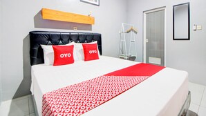 A neatly made bed with a red and white patterned bedspread, a black headboard, and two red pillows with the word "OYO" on them. - Hotel O Maryam Homestay Syariah 2 (Patuk)