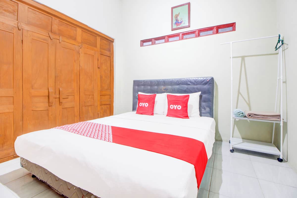 Una habitación de hotel con una cama grande, un armario de madera y un estante blanco con toallas dobladas.