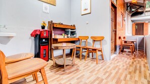A cozy room with a wooden table and chairs, a red coffee machine, and a bookshelf. - Hotel O Maryam Homestay Syariah 2 (Patuk)