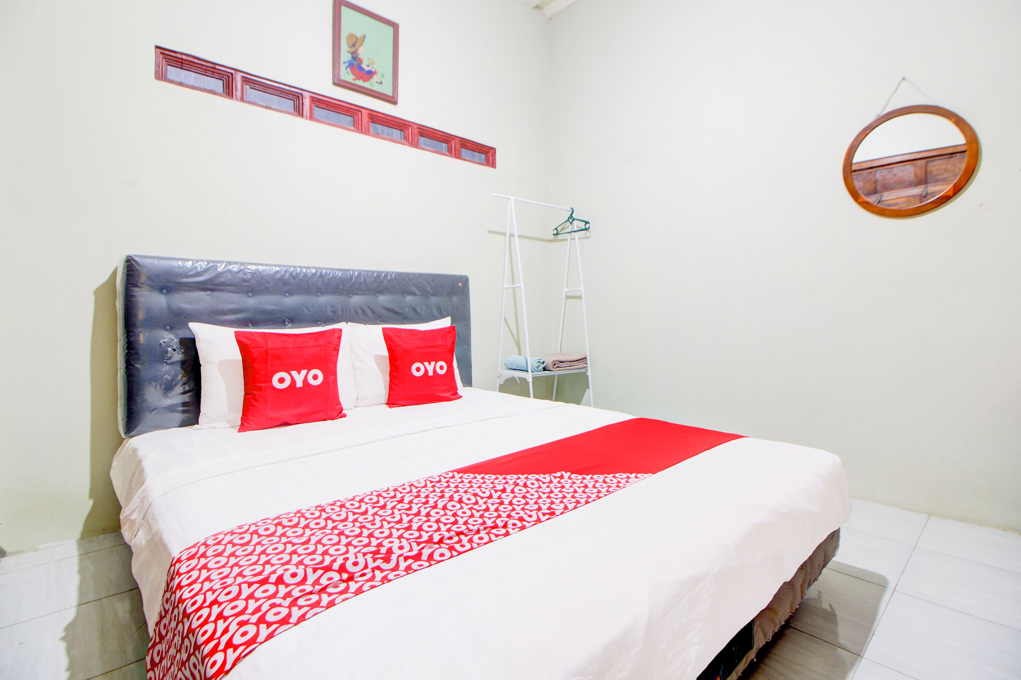 A neatly made bed with a red and white patterned bedspread and two red pillows with the word "OYO" on them.