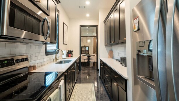 Una cocina moderna con electrodomésticos de acero inoxidable, gabinetes negros y salpicadero de azulejos.