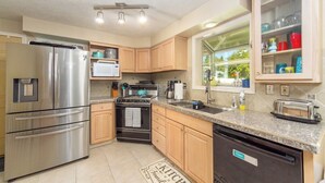 A modern kitchen with stainless steel appliances, wooden cabinets, granite countertops, and a built-in dishwasher. - Charming 3 Bed, 2 and a half Bath Family Oasis - Pool, BBQ, Fire Pit (Spokane Valley)
