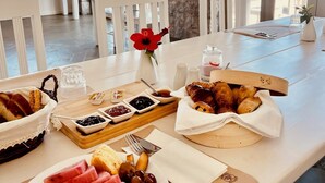 A breakfast table with croissants, jams, and fruits.