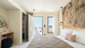 A bedroom with a large bed, a view of the outdoors, and a textured wall.