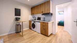 A compact kitchen with wooden cabinets, a washing machine, a microwave, and a coffee maker. - Chatillon · Renovated apartment ~ Chatillon (Châtillon)