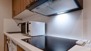 A modern kitchen with a built-in microwave, an induction cooktop, and a range hood above the cooktop. - Chatillon · Renovated apartment ~ Chatillon (Châtillon)