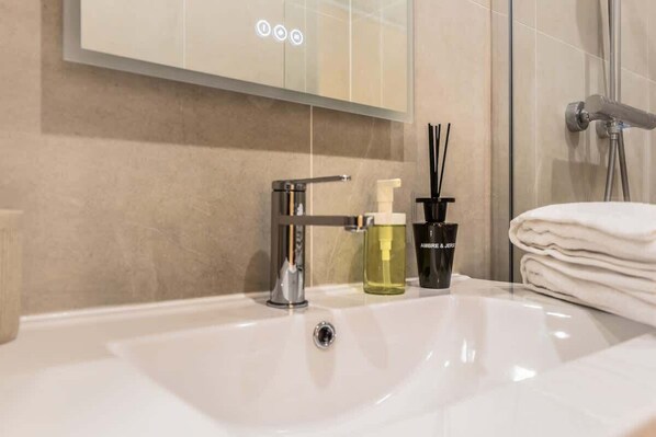 A bathroom with a white sink, a mirror, and a shower area.