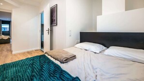 A modern hotel room with a large bed, a teal throw blanket, and a dark headboard. - Chatillon · Renovated apartment ~ Chatillon (Châtillon)