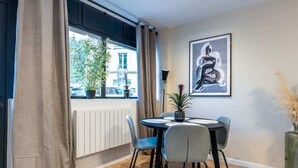 A dining area with a round table, four chairs, a potted plant, and a framed artwork on the wall. - Chatillon · Renovated apartment ~ Chatillon (Châtillon)