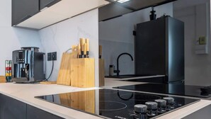 Eine moderne Küche mit einem schwarzen Induktionskochfeld, einer Kaffeemaschine und Holzkochlöffeln auf der Arbeitsfläche.