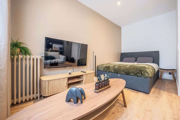 A modern bedroom with a bed, TV, and a wooden console table. - Stylish and cozy apartment with balcony (Montrouge)