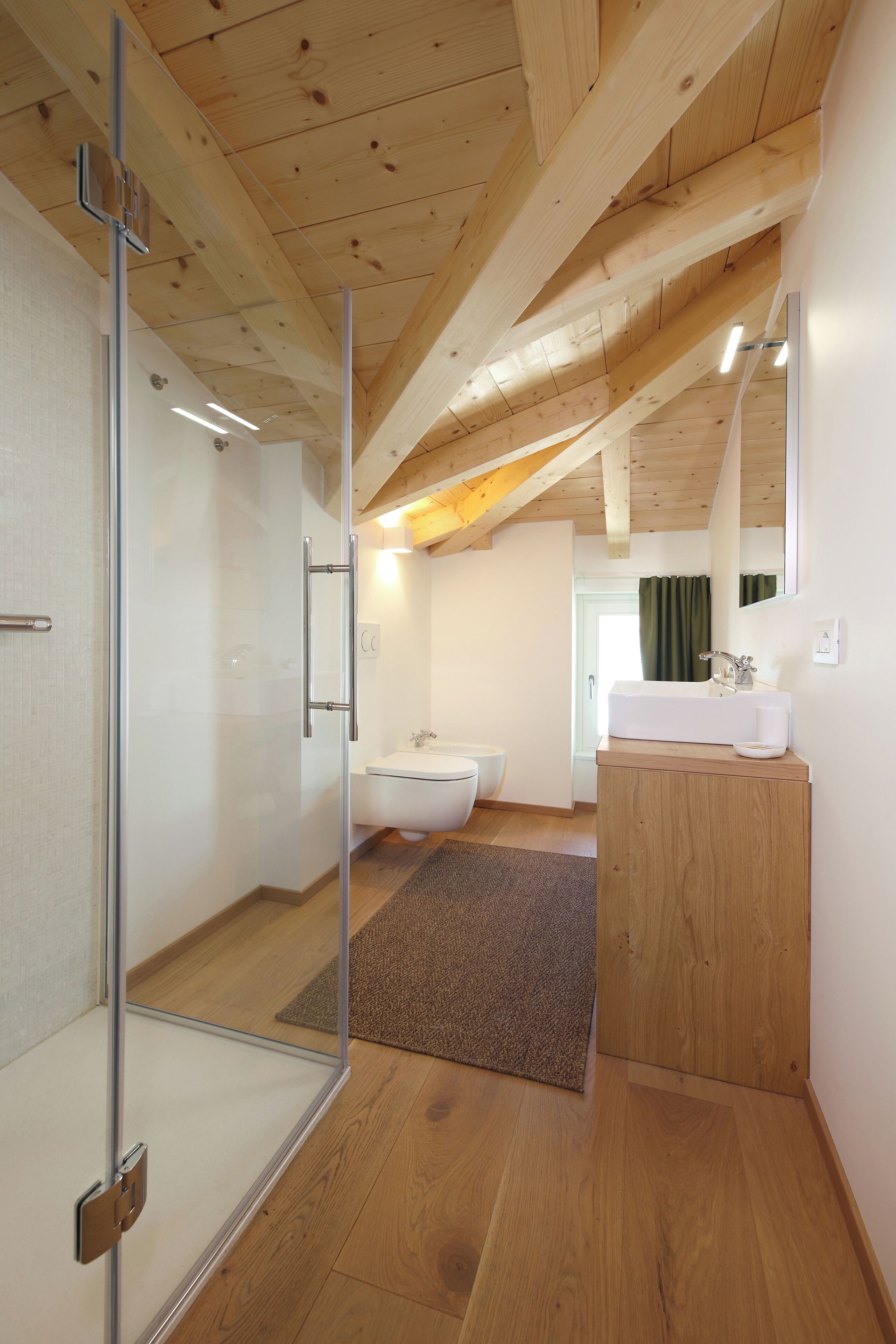 A modern bathroom with a glass shower enclosure, a wooden vanity, and a large mirror.