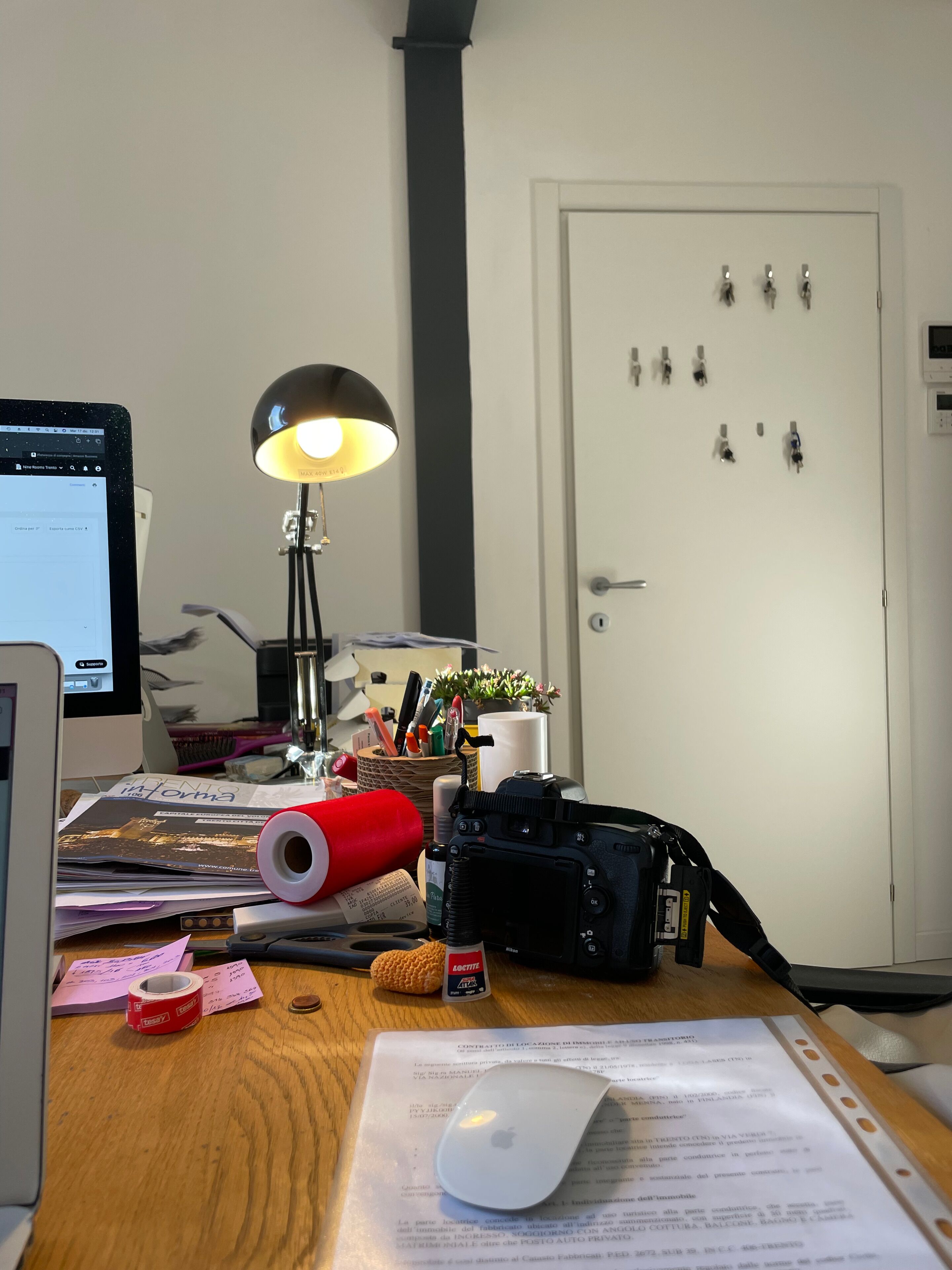 Un bureau avec un ordinateur, une lampe, un appareil photo et divers accessoires de bureau.