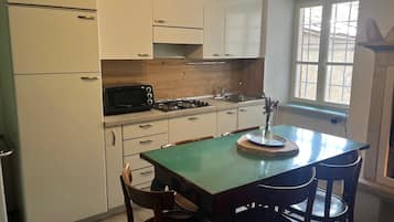 Una cocina con armarios blancos, una mesa verde y dos sillas de madera.