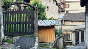 A narrow alleyway with a wooden gate, a small wooden structure, and a building with a tiled roof. - Sorriso Berzo Apartment With Stunning Views (Berzo Demo)
