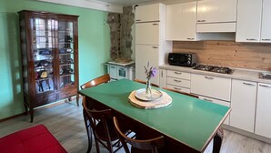 A compact kitchen with white cabinets, a green dining table, and a red chair. - Sorriso Berzo Apartment With Stunning Views (Berzo Demo)