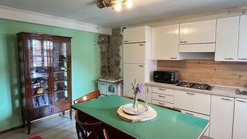 Una cucina compatta con mobili bianchi, un tavolo da pranzo verde e una sedia rossa.