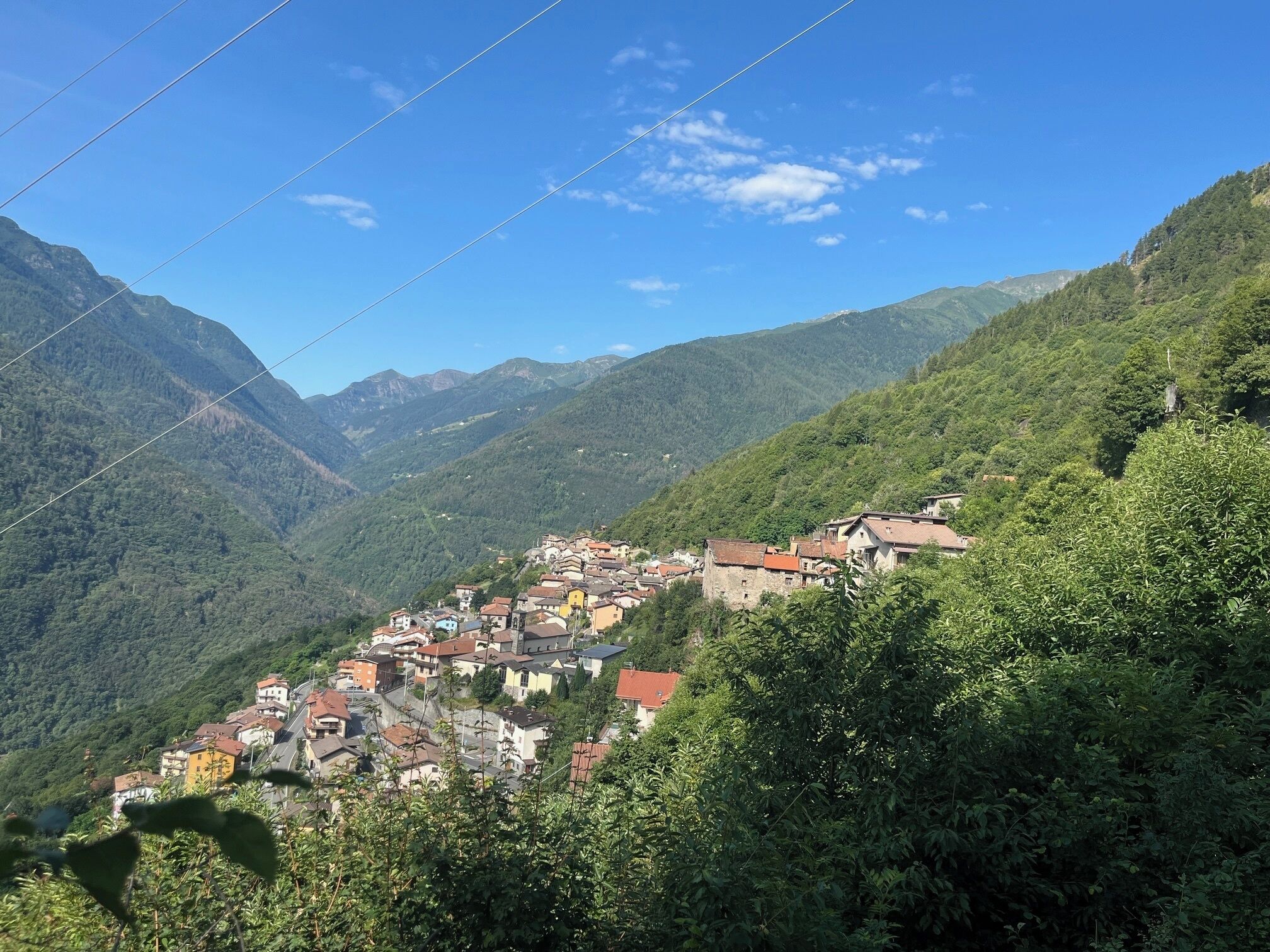A mountain village with traditional architecture nestled in a valley, surrounded by lush greenery and mountains.